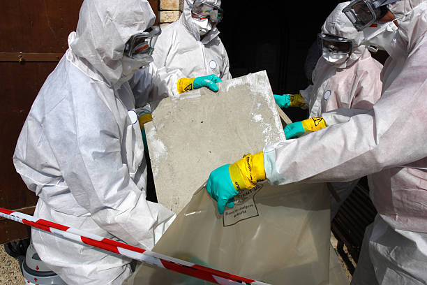 Removing materials containing some asbestos "Staff removing some asbestos in a post of transformer, Reflection of mask of man opposite was created for cannot be recognized" Asbestos Removal stock pictures, royalty-free photos & images
