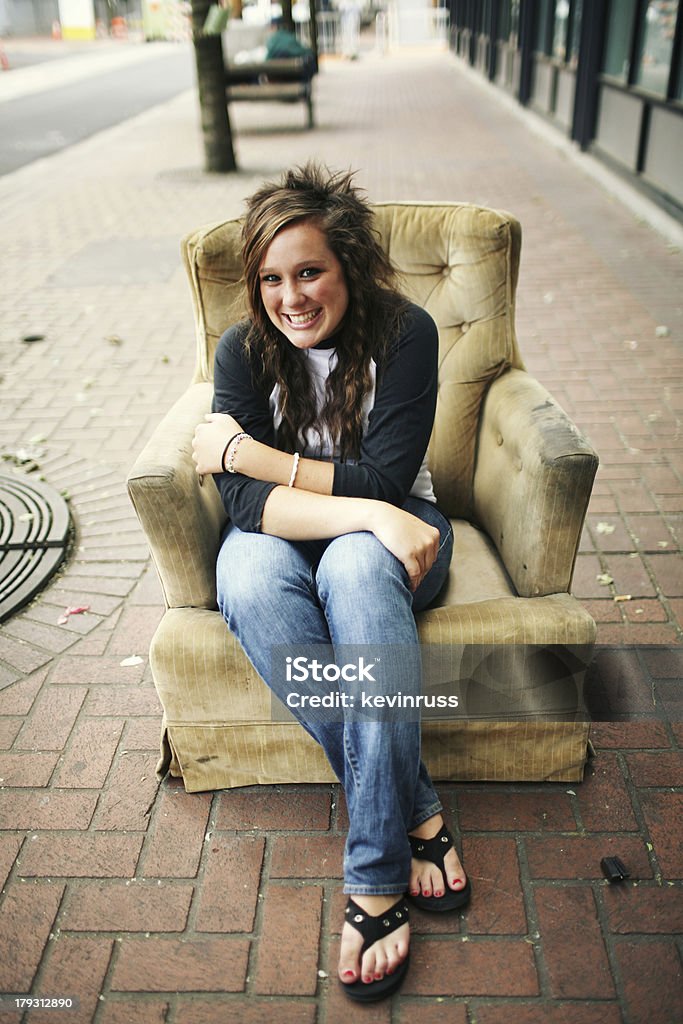 Teen fille avec des sandales assis sur une chaise sur le trottoir rustique - Photo de Adulte libre de droits