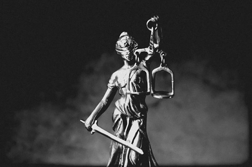 Themis statue Justice with scales on dark background with smoke. Legal and law concept