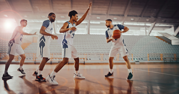 Male basketball players dribbling while playing basketball during practice on court.