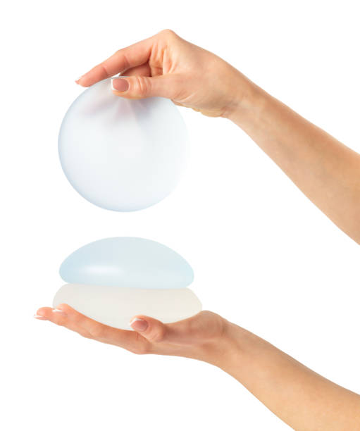 istock Hands showing round breast implants. Isolated on white background, clipping path 1793149785