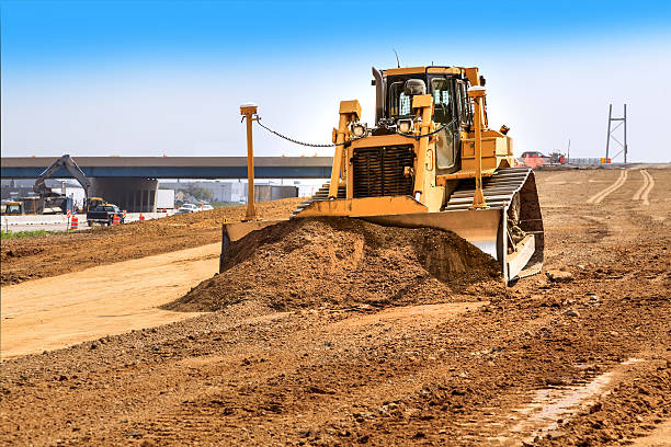 Bulldozer leveling dirt on new road stock photo