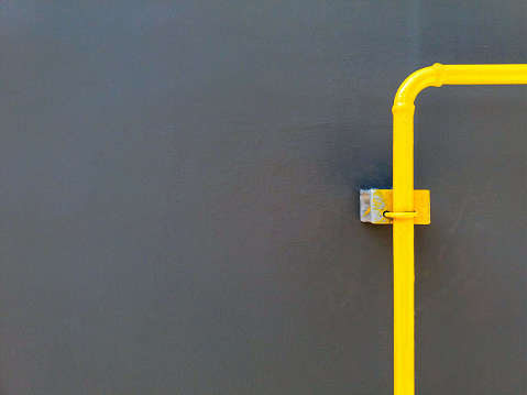Single yellow gas, oil and water pipeline on gray or black wall with copy space