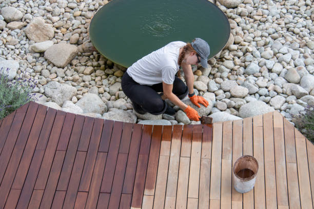 Female worker applying deck protection sealer, house terrace wood staining concept, high angle view