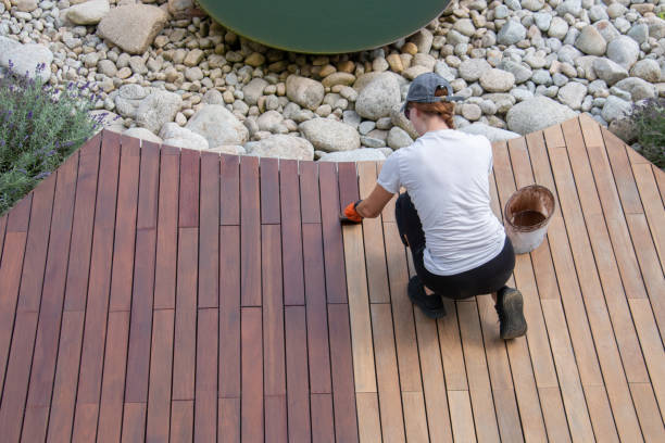 aplicación de aceite de cubierta de madera dura, mujer superior que pinta tablas de madera de tarima de jardín - varnishing hardwood decking fotografías e imágenes de stock