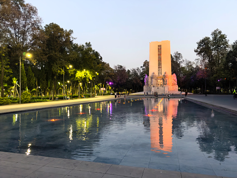 La Bombilla public park in the south of Mexico City on a weekend, with families and visitors around an illuminated fountain at sunset