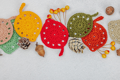 Set of clew of thread for knitting. Crocheted different leaves, handmade, autumn hobby concept. Props and special craft tools on light stone concrete background, top view