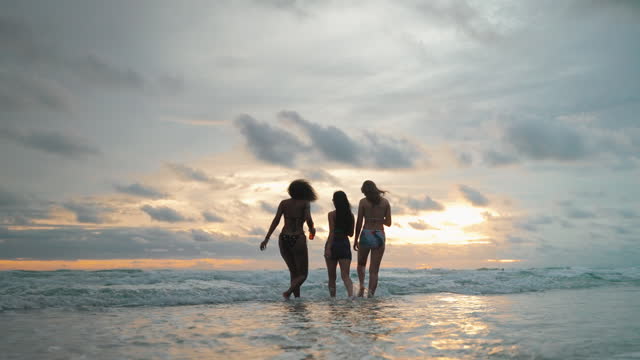 three young women having fun drinking and dancing on the beach on vacation, travel, recreation concept.