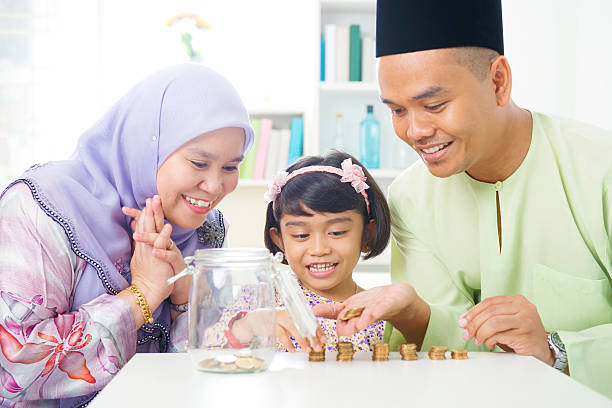 Islamic banking concept. Islamic banking concept. Southeast Asian family counting money at home. Little Malay girl and parents saving money. Muslim father, mother and daughter living lifestyle. veil photos stock pictures, royalty-free photos & images
