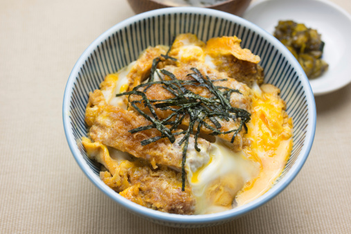 A katsudon (カツ丼) is a popular Japanese food, a bowl of rice topped with a deep-fried pork cutlet(豚カツ), egg, and condiments.