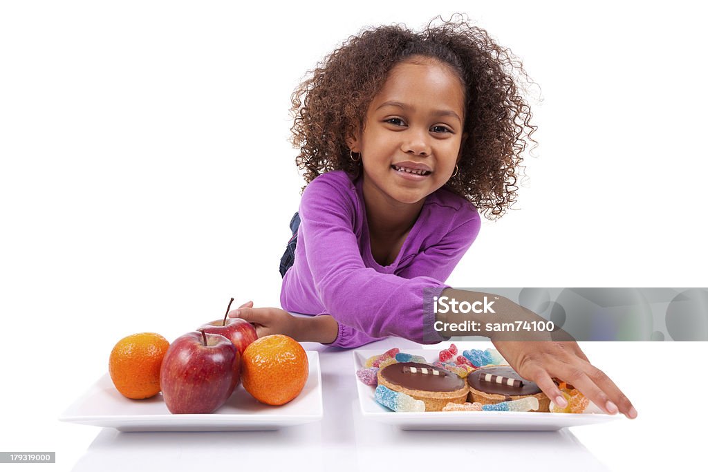 Kleine afrikanische asiatische Mädchen hesitating zwischen Obst und Süßigkeiten - Lizenzfrei Abnehmen Stock-Foto