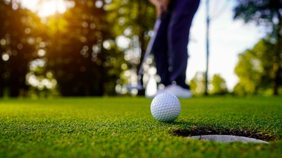 Male golf player swinging golf club.