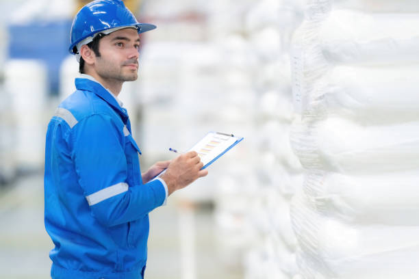 istock Side view of the American engineer manager, smiling, has a smart look. It is in a warehouse, industrial factory, business of a large company. Wearing a uniform and hard hat, holding a list of notes. 1793191879