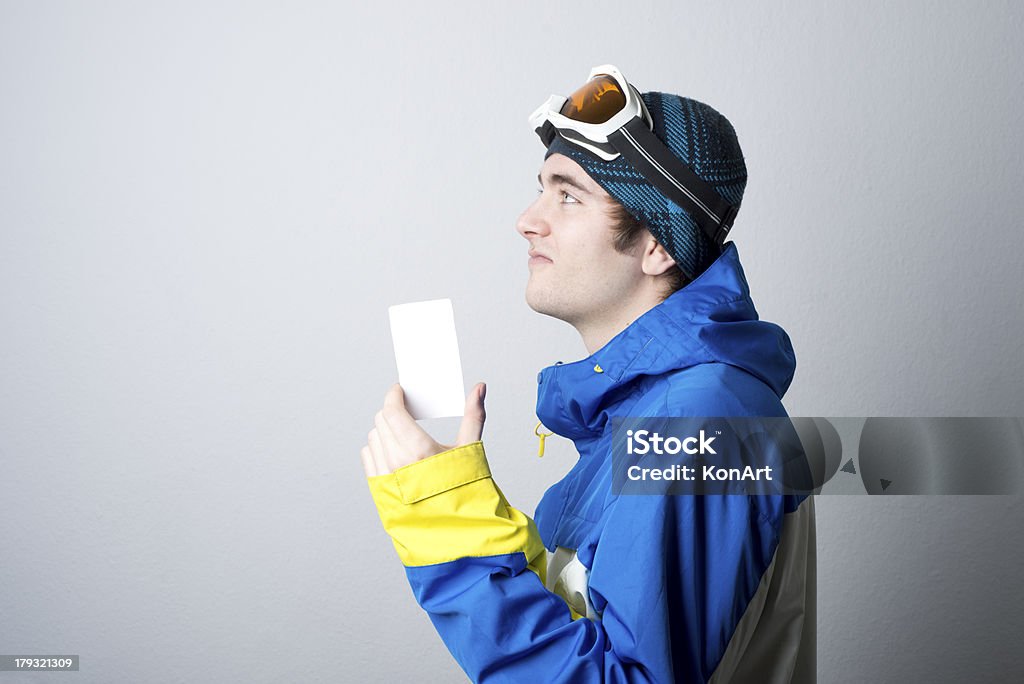 Young man holding blank lift admission ticket Blank ski lift pass in hand of young man with winter outfit looking at corner Adults Only Stock Photo