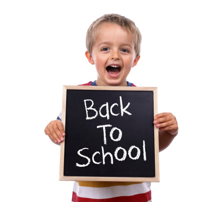 Young child holding back to school chalk blackboard sign standing against white background