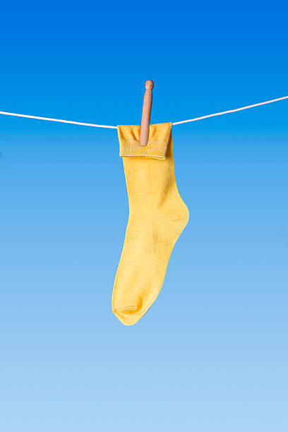 yellow sock and wooden dolly peg on washing line