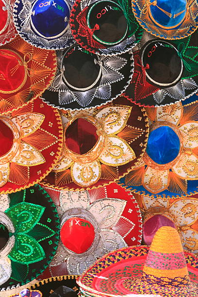 A collection of colorful sombreros in the Cancun, Mexico.  Each sombrero has a plain cap surrounded by ornate floral and geometric designs.  Most are red, blue, green or black with ivory or multicolored designs.