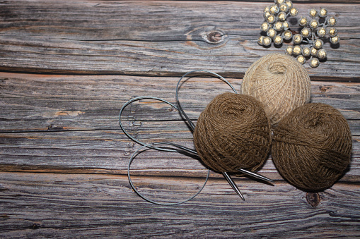 brown yarn on wooden textured background and two crochet. Needle.