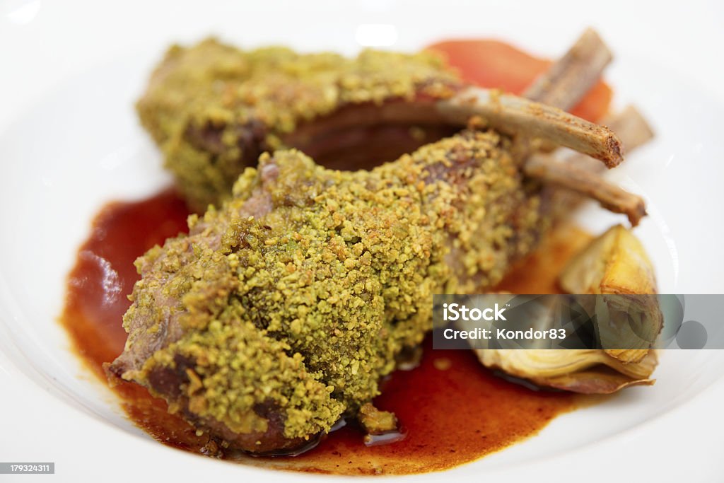 Grilled rack of lamb on plate Grilled rack of lamb with pistachio and artichokes on plate, close-up Rack of Lamb Stock Photo