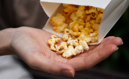 Woman holding popcorn cheese in a paper bag  in the hand