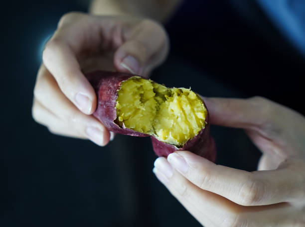 アジアの女性がサツマイモの皮をむいている、クローズアップショット。 - root vegetable raw potato human skin root ストックフォトと画像