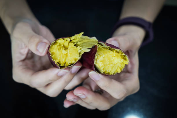 アジアの女性がサツマイモの皮をむいている、クローズアップショット。 - root vegetable raw potato human skin root ストックフォトと画像