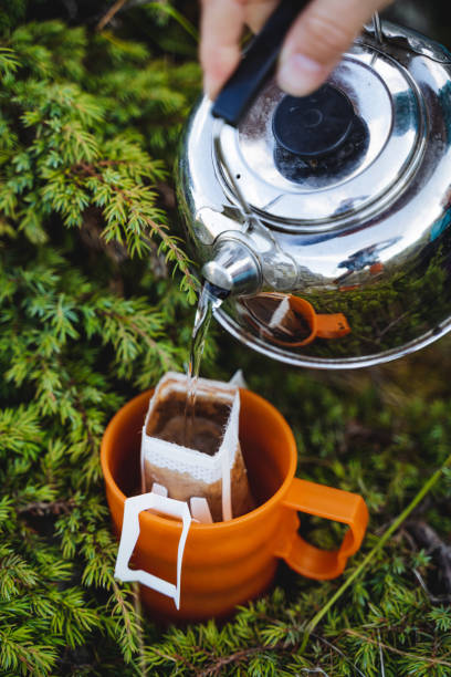 istock Filter coffee package brew with boiling water, pour hot coffee into a glass, silver metal kettle, coffee drink, finely ground beans. water pours from the kettle. 1793260949
