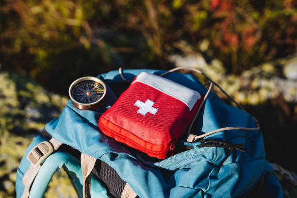 istock Compass first aid kit are in a backpack, a navigator in the taiga, a first aid kit in emergency situations, a white cross, medicines in a red bag. 1793262085