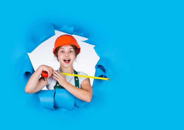 istock construction worker with tape measure. Cute kid as a construction worker. kid repairing home. happy childhood. self-retracting metal tape measure. Little girl using a measuring tape. copy space 1793262089