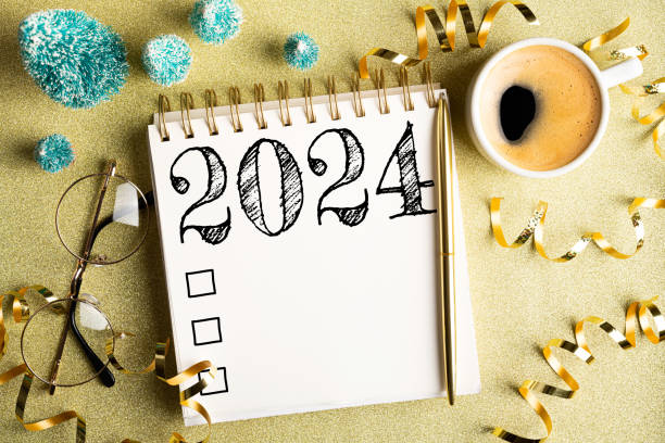 istock 2024 New year resolutions on desk. 2024 goals list with notebook, coffee cup, festive decorations on golden background. Resolutions, plan, goals, checklist, idea concept. New Year 2024 resolutions 1793288483