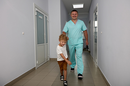 nimble boy leads doctor by hand down the corridor of the hospital for procedure