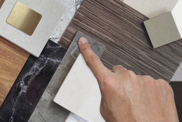 istock close up view of interior architect's hand picks material samples including black and gery marble stones, wooden vinyl flooring tiles, quartz, ceramic tiles, walnut veneer, terrazzo stone, stainless. 1793298653