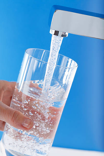 istock Filling up a glass of water . Blue background 179330570
