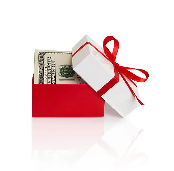 U.S. dollars banknotes laying in red bow decorated gift box.