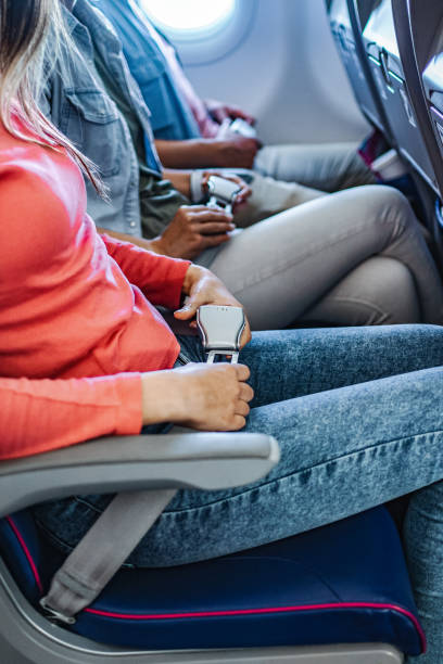 istock Passengers on an airplane flight adjusting seat belts 1793310011