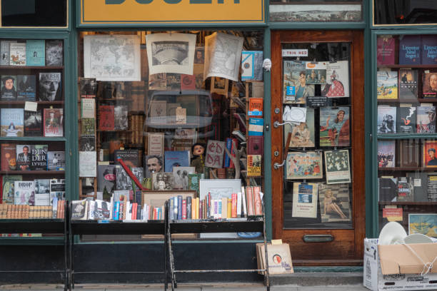 Front window of small antiquarian shop selling books, cards, magazines, prints and old maps. Copenhagen, Denmark - November 13, 2023.