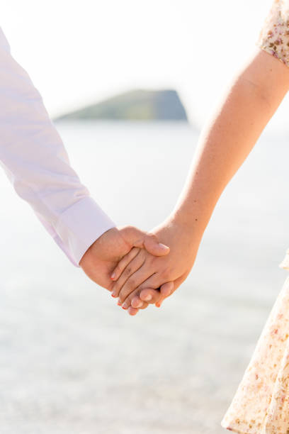 istock Man holds woman hand while standing on the seashore. Cropped. Faceless 1793330261