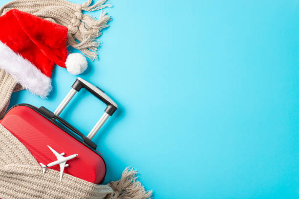 istock Santa's Airborne Trip: Overhead composition featuring a red suitcase, small plane model, Santa's outfit, and wintry details against a snowy blue backgroundâperfect for your festive greetings 1793330292