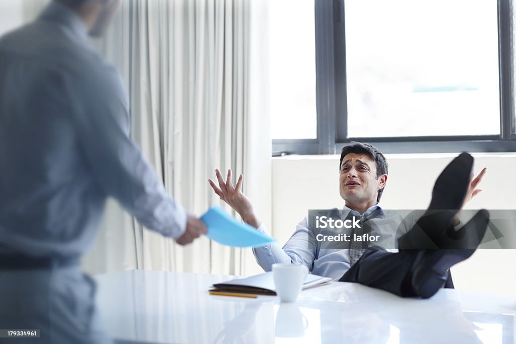 What's the problem?! An irritated businessman with his feet up on his desk as a coworker stands by Manager Stock Photo