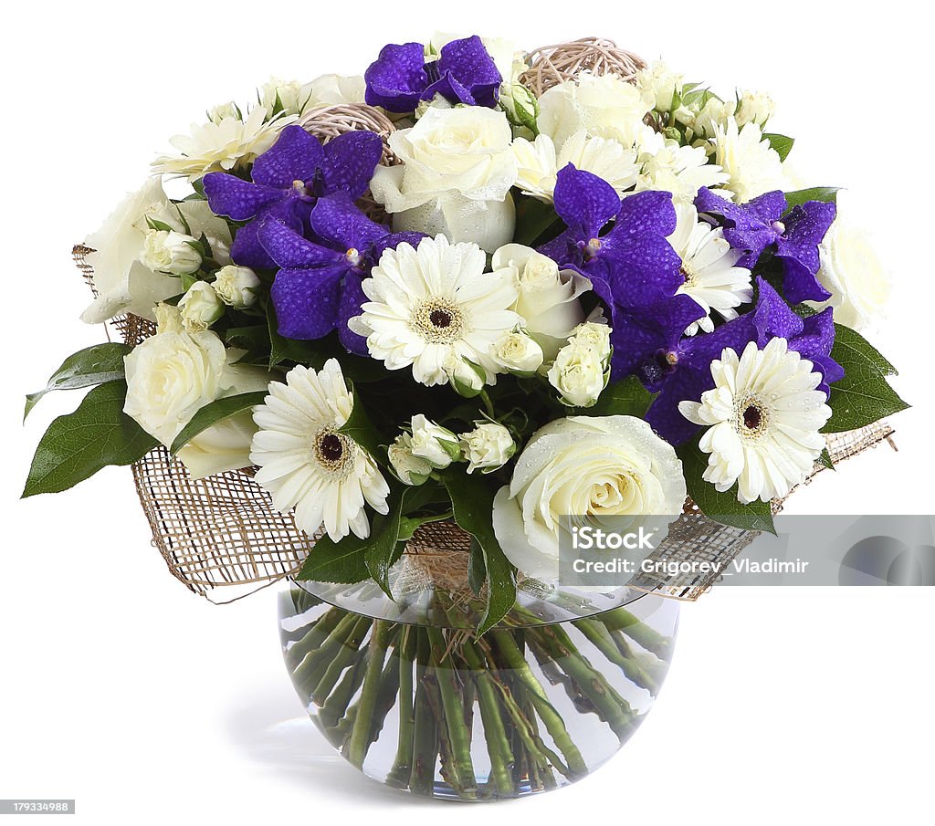 Floral composition in glass, transparent vase: White roses, viol Flower arrangement in glass, transparent vase: White roses, purple orchids, white gerbera daisies, green peas. Isolated on white background. Floristic composition, design a bouquet, floral arrangement. Violet orchids. Bouquet Stock Photo