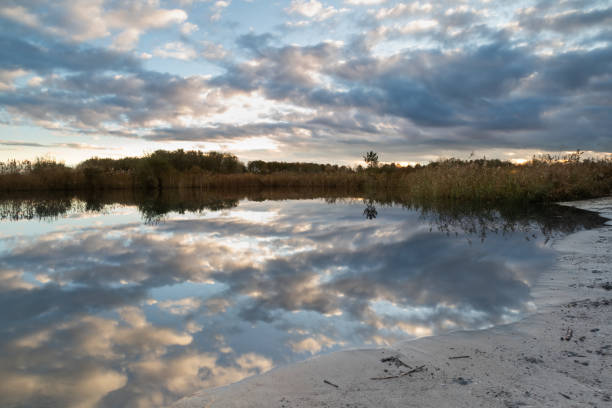 spiegelung des bewölkten himmels im see des naherholungsgebietes geestmerambacht. während des sonnenuntergangs zogen die typisch holländischen wolken vorbei und spiegelten sich im ruhigen wasser. doppelter genuss! - drifted stock-fotos und bilder