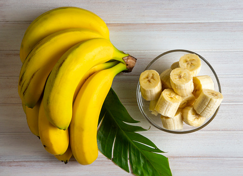 Ripe yellow bananas and cuts of peeled banana on white background. File contains clipping path.