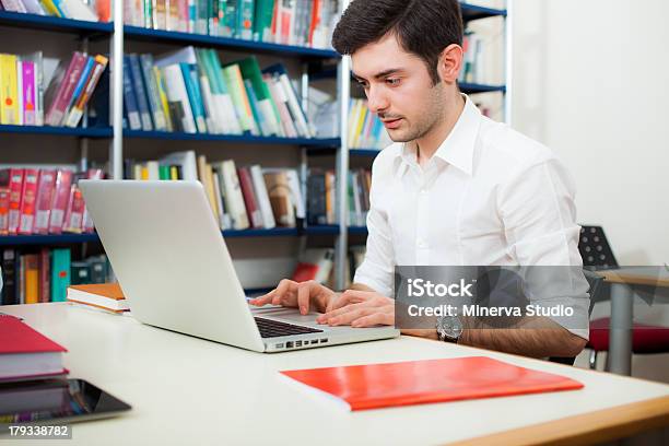 Ragazzo Usando Il Suo Computer Portatile In Una Libreria - Fotografie stock e altre immagini di Cercare