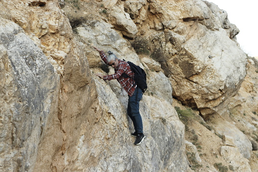 A businessman stands with a look of concern as he is trapped between a rock and a hard place.