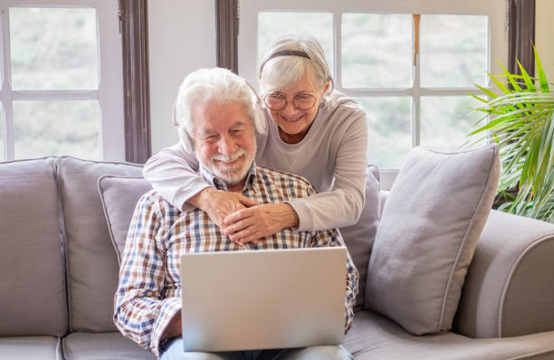 istock Happy 70s white-haired senior couple relaxing on home couch, looking in internet store using laptop, shopping together online. Old generation and wireless technology users 1793403852