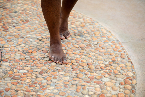 A South Indian man's feet walk over acupressure stones in a public park.