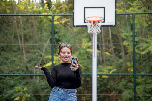 Young beautiful blonde woman on basketball court in autumn