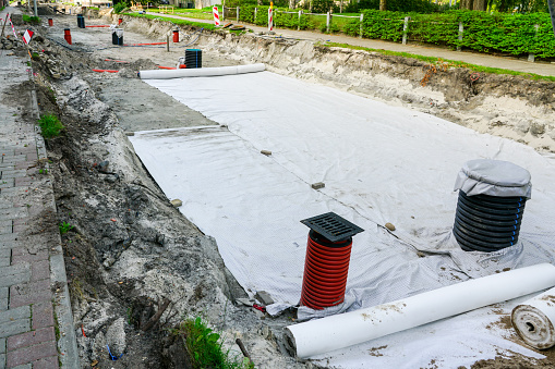 Use of geotextile fabric rolls for drainage and separation of base layers in street reconstruction, plastic wells