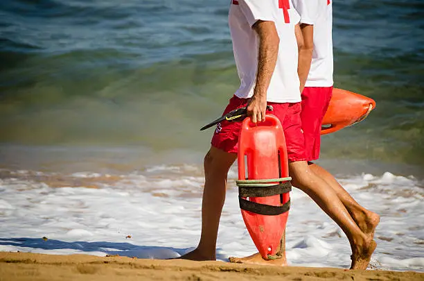 Lifeguards walking on the beach; no logos; outdoor photography.