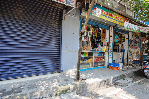 Chennai, India - October 17, 2023. One shop is closed while next door a shop is open in Chennai, Tamil Nadu, India.